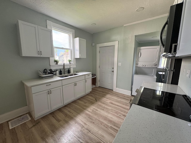 1345 E Livingston Ave Unit 1347, Columbus, OH 43205 - kitchen with stacked washer / drying machine, white cabinets, light countertops, and a textured ceiling