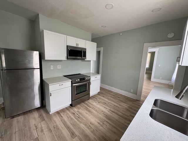 1345 E Livingston Ave Unit 1347, Columbus, OH 43205 - kitchen featuring appliances with stainless steel finishes, light wood-style flooring, and white cabinets