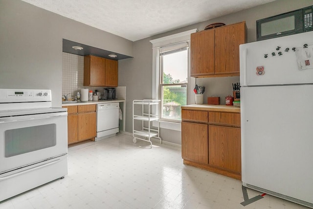 2521 Glenmawr Ave, Columbus, OH 43202 - kitchen with white appliances, light countertops, light floors, brown cabinets, and backsplash