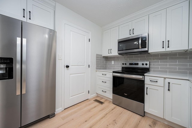 260 Old Coach Pl, Canal Winchester, OH 43110 - kitchen featuring appliances with stainless steel finishes, light countertops, light wood-style floors, tasteful backsplash, and a textured ceiling