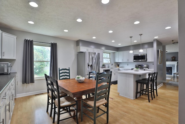 677 Fallside Ln, Westerville, OH 43081 - dining space with recessed lighting, light wood-style flooring, a textured ceiling, and a glass covered fireplace