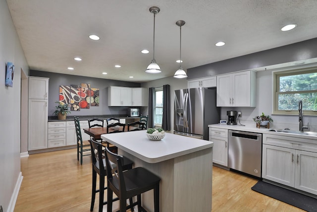 677 Fallside Ln, Westerville, OH 43081 - kitchen with stainless steel appliances, light wood finished floors, white cabinetry, a kitchen bar, and a center island