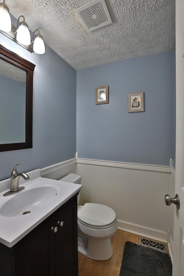 677 Fallside Ln, Westerville, OH 43081 - bathroom with wainscoting, wood finished floors, vanity, and a textured ceiling