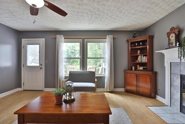 677 Fallside Ln, Westerville, OH 43081 - living room featuring a fireplace, light wood-style flooring, ceiling fan, and a textured ceiling