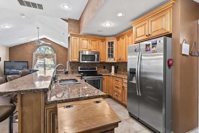2919 Laurel Wind Blvd, Lewis Center, OH 43035 - kitchen featuring appliances with stainless steel finishes, a peninsula, lofted ceiling, a kitchen breakfast bar, and glass insert cabinets