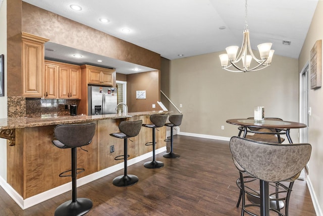 2919 Laurel Wind Blvd, Lewis Center, OH 43035 - kitchen featuring stainless steel refrigerator with ice dispenser, dark wood-style flooring, stone countertops, a kitchen bar, and recessed lighting
