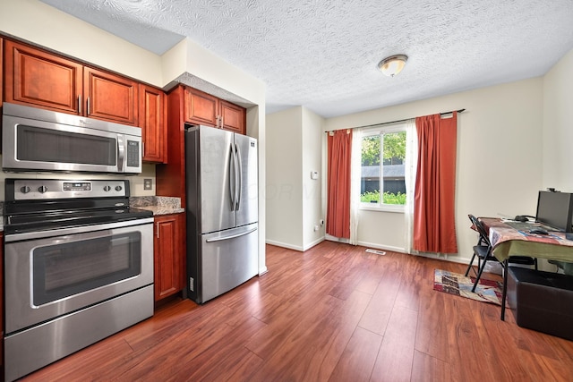 3254 Brookview Way Unit 15, Columbus, OH 43221 - kitchen with appliances with stainless steel finishes, dark wood-style flooring, a textured ceiling, brown cabinetry, and light stone counters