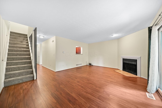 3254 Brookview Way Unit 15, Columbus, OH 43221 - unfurnished living room featuring wood finished floors, stairway, and a fireplace with flush hearth