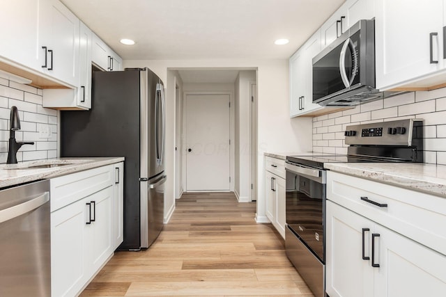 5110 Schuylkill St Unit 33-10, Columbus, OH 43220 - kitchen featuring stainless steel appliances, light wood-type flooring, white cabinetry, recessed lighting, and light stone countertops
