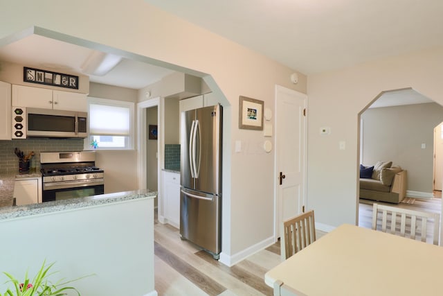 822 Rutter Ave, Lancaster, OH 43130 - kitchen with appliances with stainless steel finishes, arched walkways, light wood-type flooring, and white cabinetry