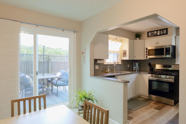 822 Rutter Ave, Lancaster, OH 43130 - kitchen with appliances with stainless steel finishes, light wood-type flooring, decorative backsplash, white cabinetry, and healthy amount of natural light