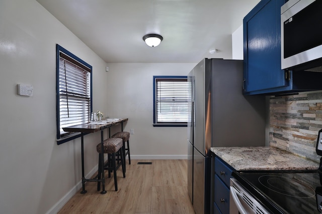 69 Morse Rd, Columbus, OH 43214 - kitchen featuring blue cabinets, stainless steel appliances, light wood-style flooring, and backsplash