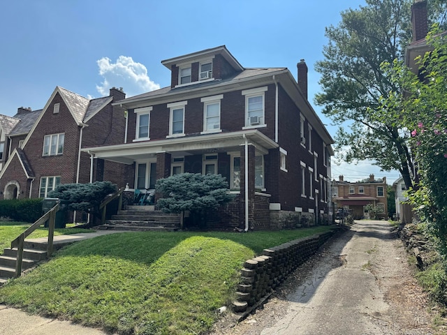 2395 Summit St, Columbus, OH 43202 - traditional style home featuring brick siding, covered porch, a front yard, a chimney, and driveway