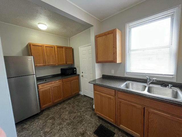 2395 Summit St, Columbus, OH 43202 - kitchen featuring freestanding refrigerator, dark countertops, brown cabinets, black microwave, and crown molding