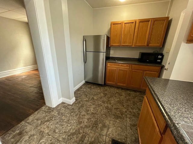 2395 Summit St, Columbus, OH 43202 - kitchen with freestanding refrigerator, brown cabinetry, dark countertops, and ornamental molding