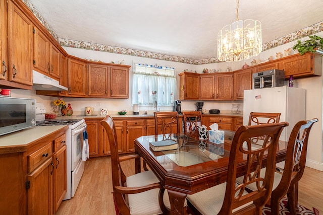 83 2nd St, Shelby, OH 44875 - kitchen with white appliances, under cabinet range hood, brown cabinetry, and light wood finished floors