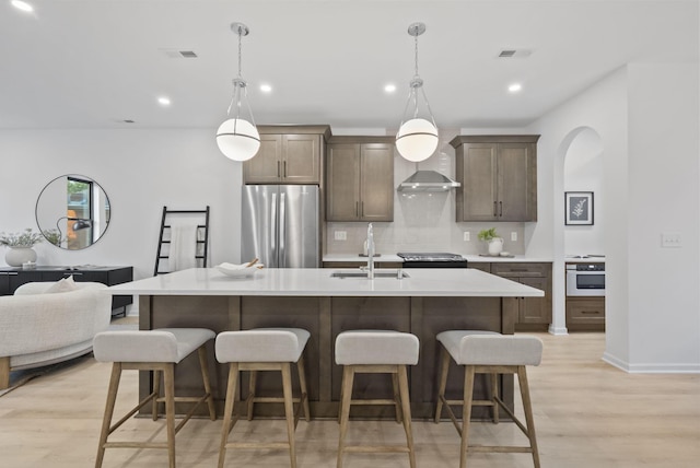 583 E Walnut St, Columbus, OH 43215 - kitchen featuring stainless steel appliances, tasteful backsplash, light wood-style flooring, a center island with sink, and recessed lighting