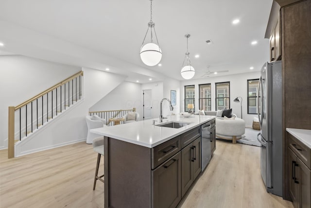 583 E Walnut St, Columbus, OH 43215 - kitchen featuring open floor plan, stainless steel appliances, dark brown cabinets, light wood-style floors, and a kitchen bar