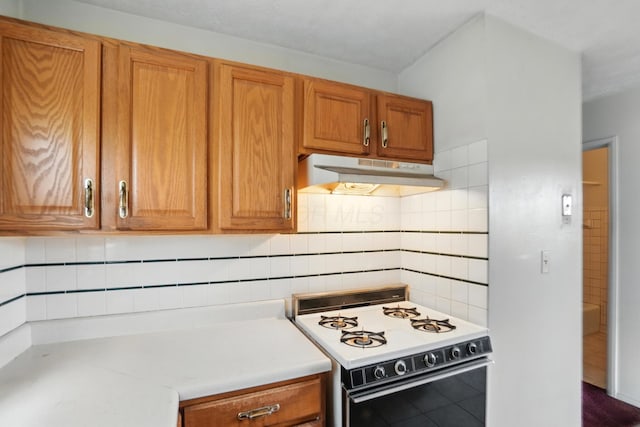 617 Athens St, Columbus, OH 43204 - kitchen featuring white gas range oven, under cabinet range hood, decorative backsplash, brown cabinetry, and light countertops