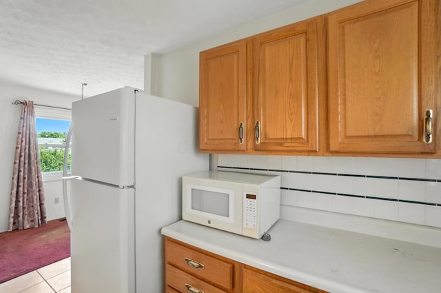 617 Athens St, Columbus, OH 43204 - kitchen featuring white appliances, light countertops, brown cabinetry, tasteful backsplash, and light tile patterned floors