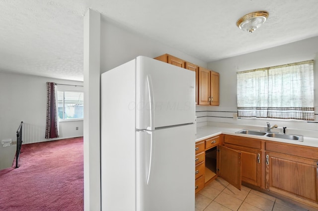 617 Athens St, Columbus, OH 43204 - kitchen featuring freestanding refrigerator, light countertops, light colored carpet, brown cabinets, and a textured ceiling