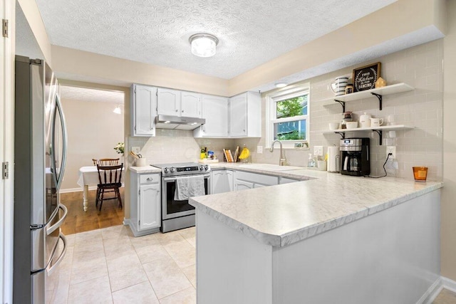 7107 Stone Ct, Columbus, OH 43235 - kitchen with stainless steel appliances, a peninsula, under cabinet range hood, light countertops, and tasteful backsplash