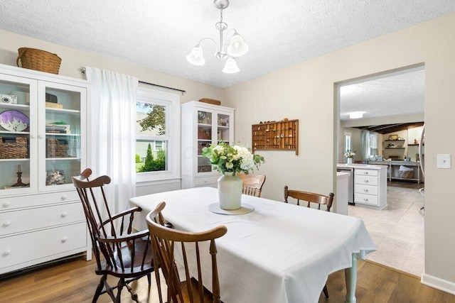 7107 Stone Ct, Columbus, OH 43235 - dining area featuring a chandelier, light wood-style flooring, and a textured ceiling