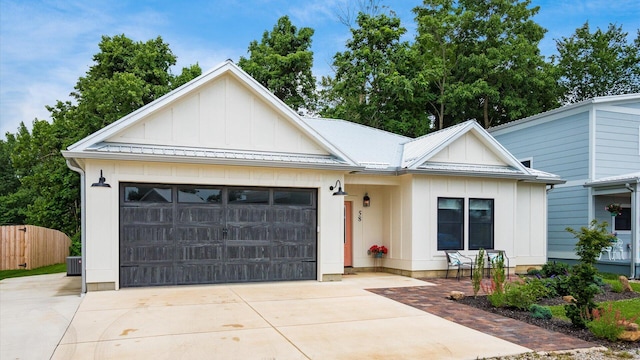 58 Lippert Ln, Buckeye Lake, OH 43008 - view of front of house with board and batten siding, concrete driveway, an attached garage, and a metal roof