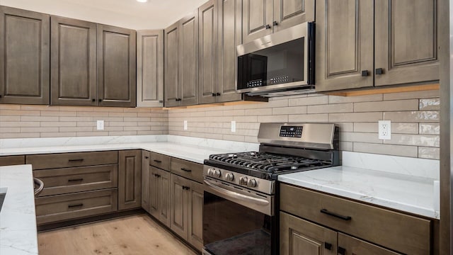 58 Lippert Ln, Buckeye Lake, OH 43008 - kitchen featuring stainless steel appliances, light wood-style floors, light stone countertops, tasteful backsplash, and dark brown cabinets