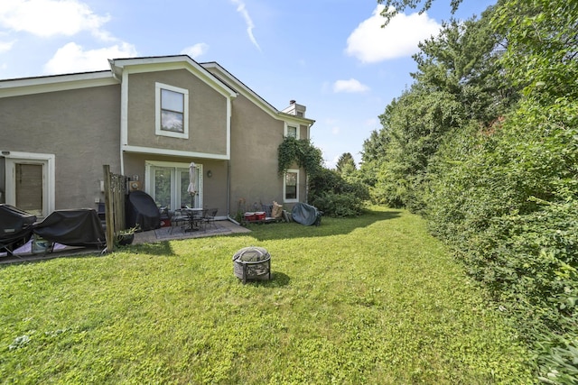 1290 Paddington Ct, Columbus, OH 43230 - back of house with stucco siding, a lawn, a chimney, a patio area, and an outdoor fire pit