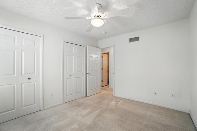 6281 Mcnaughten Place Ln Unit 24, Columbus, OH 43213 - unfurnished bedroom featuring two closets, light colored carpet, a textured ceiling, and ceiling fan