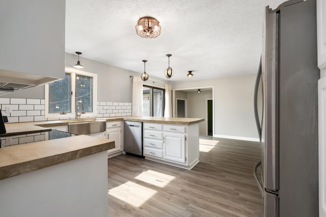 1242 Springbrook Dr, Mansfield, OH 44906 - kitchen featuring stainless steel appliances, decorative backsplash, a peninsula, white cabinetry, and wood finished floors