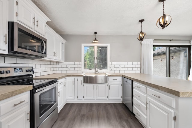 1242 Springbrook Dr, Mansfield, OH 44906 - kitchen with appliances with stainless steel finishes, a peninsula, plenty of natural light, a textured ceiling, and dark wood-style flooring