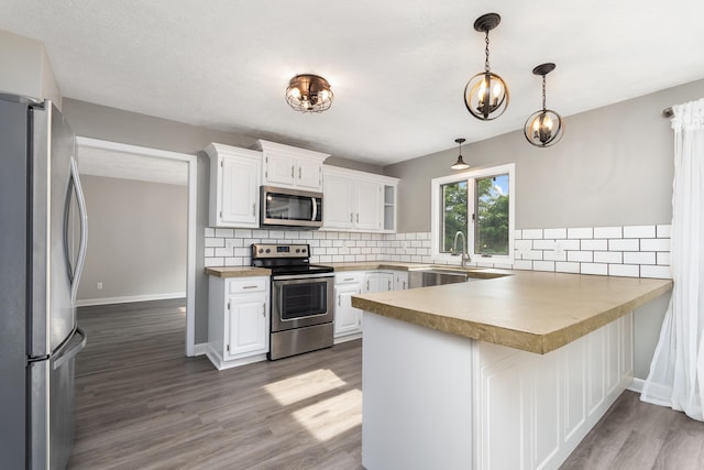 1242 Springbrook Dr, Mansfield, OH 44906 - kitchen featuring a peninsula, stainless steel appliances, wood finished floors, decorative backsplash, and white cabinets