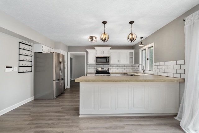 1242 Springbrook Dr, Mansfield, OH 44906 - kitchen with appliances with stainless steel finishes, a peninsula, light countertops, tasteful backsplash, and a chandelier