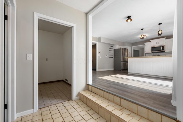 1242 Springbrook Dr, Mansfield, OH 44906 - kitchen with appliances with stainless steel finishes, white cabinets, tile patterned floors, a peninsula, and hanging light fixtures