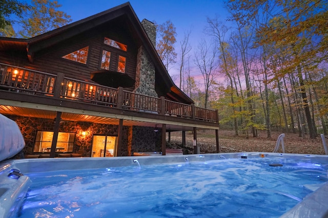 16651 Skinner Rd, Logan, OH 43138 - back of property at dusk featuring a hot tub, stone siding, a chimney, and a wooden deck