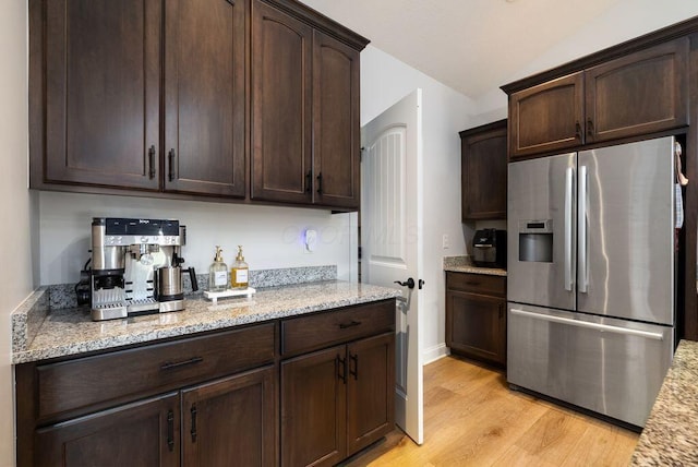 4881 Hoover Rd, Grove City, OH 43123 - kitchen with stainless steel fridge with ice dispenser, vaulted ceiling, dark brown cabinetry, light wood-style flooring, and light stone countertops