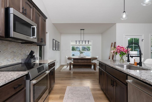4881 Hoover Rd, Grove City, OH 43123 - kitchen featuring appliances with stainless steel finishes, tasteful backsplash, dark brown cabinets, and hanging light fixtures