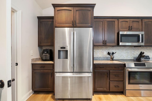 4881 Hoover Rd, Grove City, OH 43123 - kitchen featuring appliances with stainless steel finishes, light wood-type flooring, dark brown cabinets, tasteful backsplash, and light stone counters