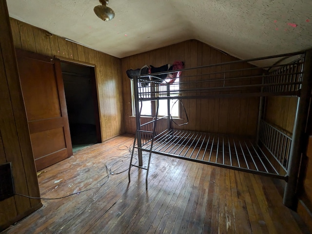 1325 Smith Rd, Columbus, OH 43207 - unfurnished bedroom with hardwood / wood-style floors, vaulted ceiling, and wood walls