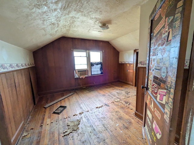 1325 Smith Rd, Columbus, OH 43207 - additional living space featuring hardwood / wood-style floors, vaulted ceiling, wooden walls, and a textured ceiling