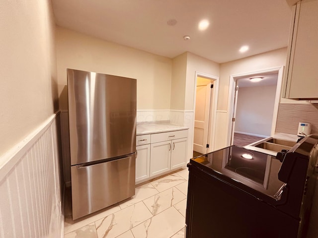 3067 E 13th Ave, Columbus, OH 43219 - kitchen featuring freestanding refrigerator, light marble finish flooring, wainscoting, black range with electric stovetop, and white cabinetry