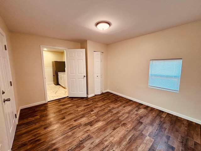 3067 E 13th Ave, Columbus, OH 43219 - unfurnished bedroom with dark wood-style flooring, connected bathroom, a closet, and freestanding refrigerator