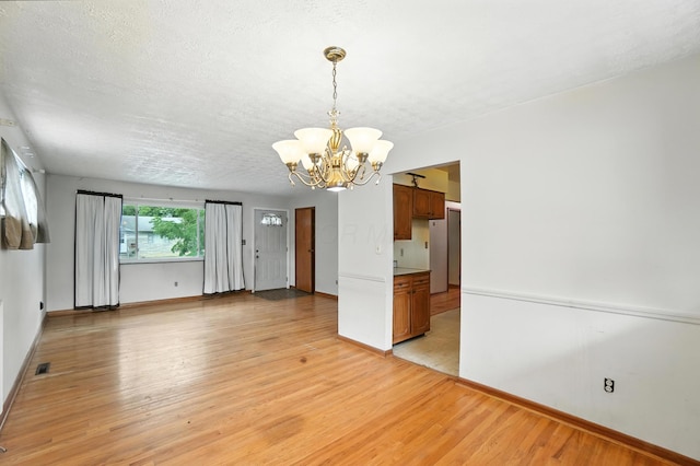 3563 Astor Ave, Columbus, OH 43227 - spare room with a chandelier, light wood-style flooring, and a textured ceiling