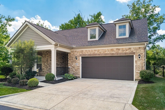 4881 Primrose Ct, Grove City, OH 43123 - view of front of home featuring stone siding, concrete driveway, a garage, roof with shingles, and covered porch