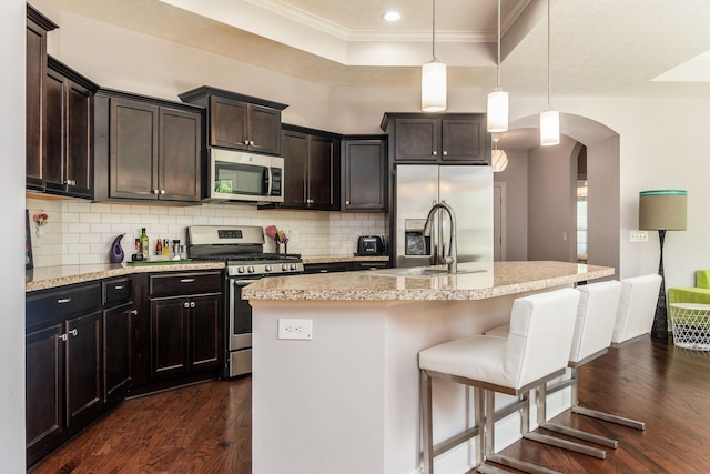 4881 Primrose Ct, Grove City, OH 43123 - kitchen featuring stainless steel appliances, ornamental molding, arched walkways, dark wood-style floors, and backsplash