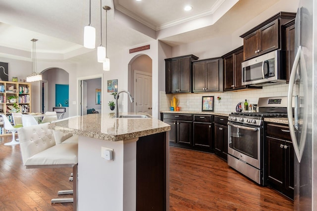 4881 Primrose Ct, Grove City, OH 43123 - kitchen featuring stainless steel appliances, a raised ceiling, arched walkways, crown molding, and dark wood finished floors