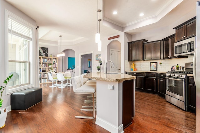 4881 Primrose Ct, Grove City, OH 43123 - kitchen with appliances with stainless steel finishes, a tray ceiling, arched walkways, dark wood-type flooring, and decorative backsplash