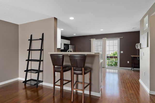 3839 Rubythroat Dr, Columbus, OH 43230 - kitchen featuring freestanding refrigerator, dark wood-style flooring, white cabinetry, a breakfast bar area, and light countertops